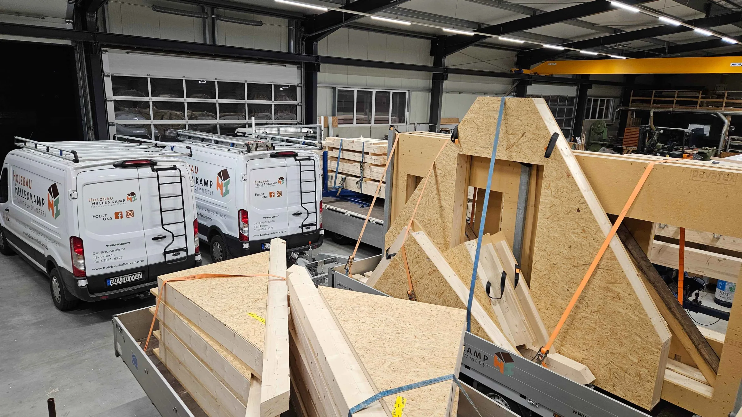 Halle von Holzbau Hellenkamp mit Firmenwagen und vorgefertigten Holzbauteilen